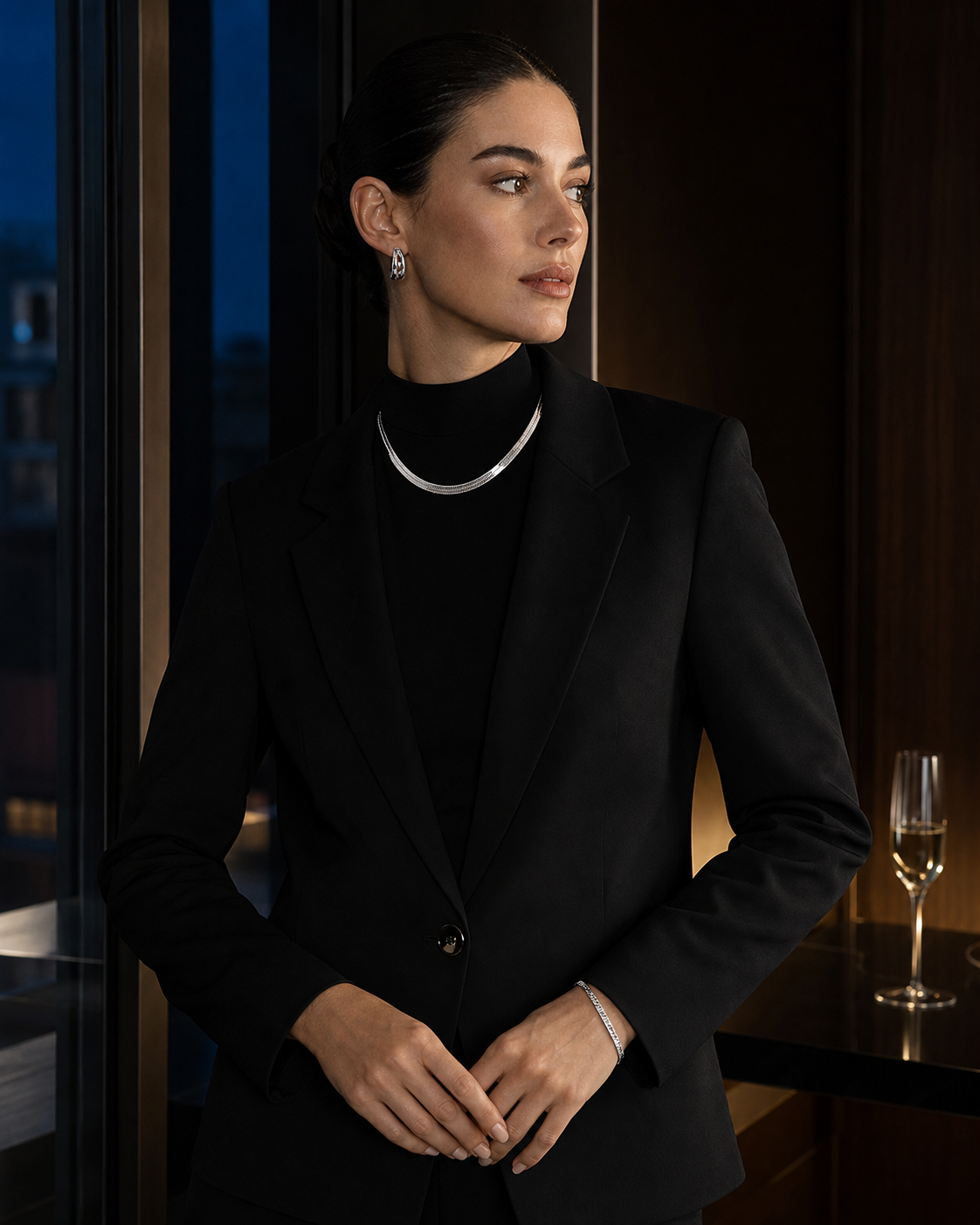 Woman wearing polished silver-tone jewelry with black tailoring