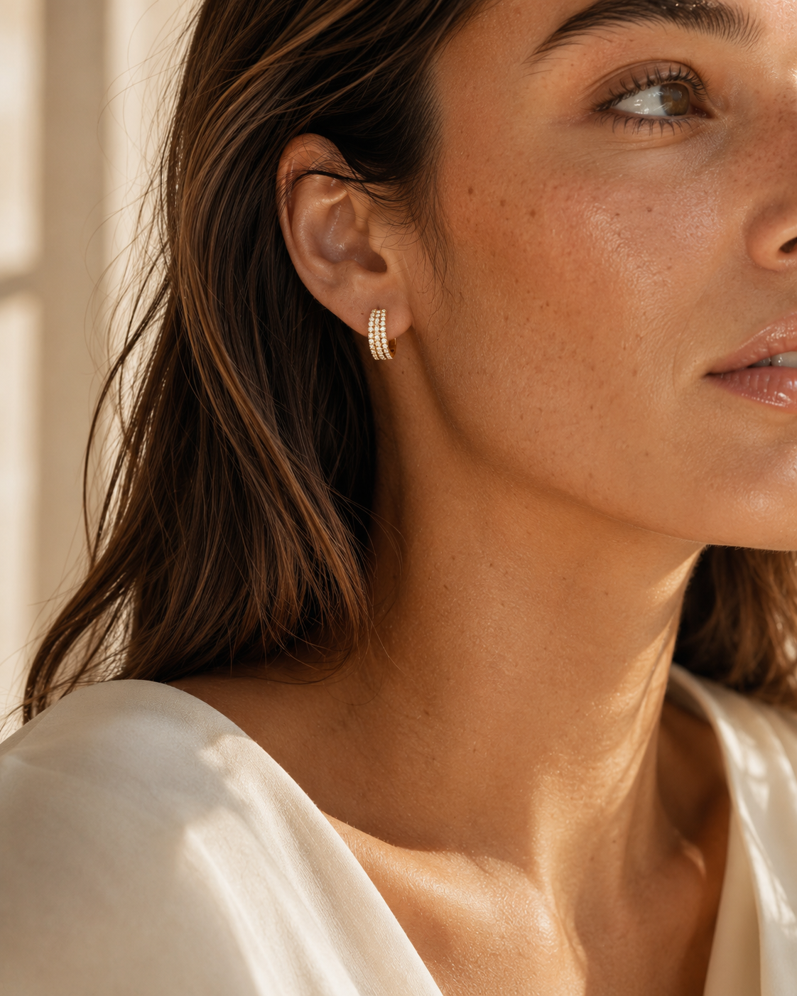 Model wearing gold-tone pavé hoop earrings