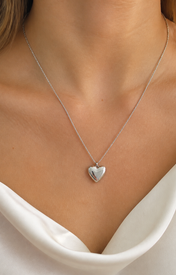 Model wearing Cora Heart Pendant in silver [finish:silver]