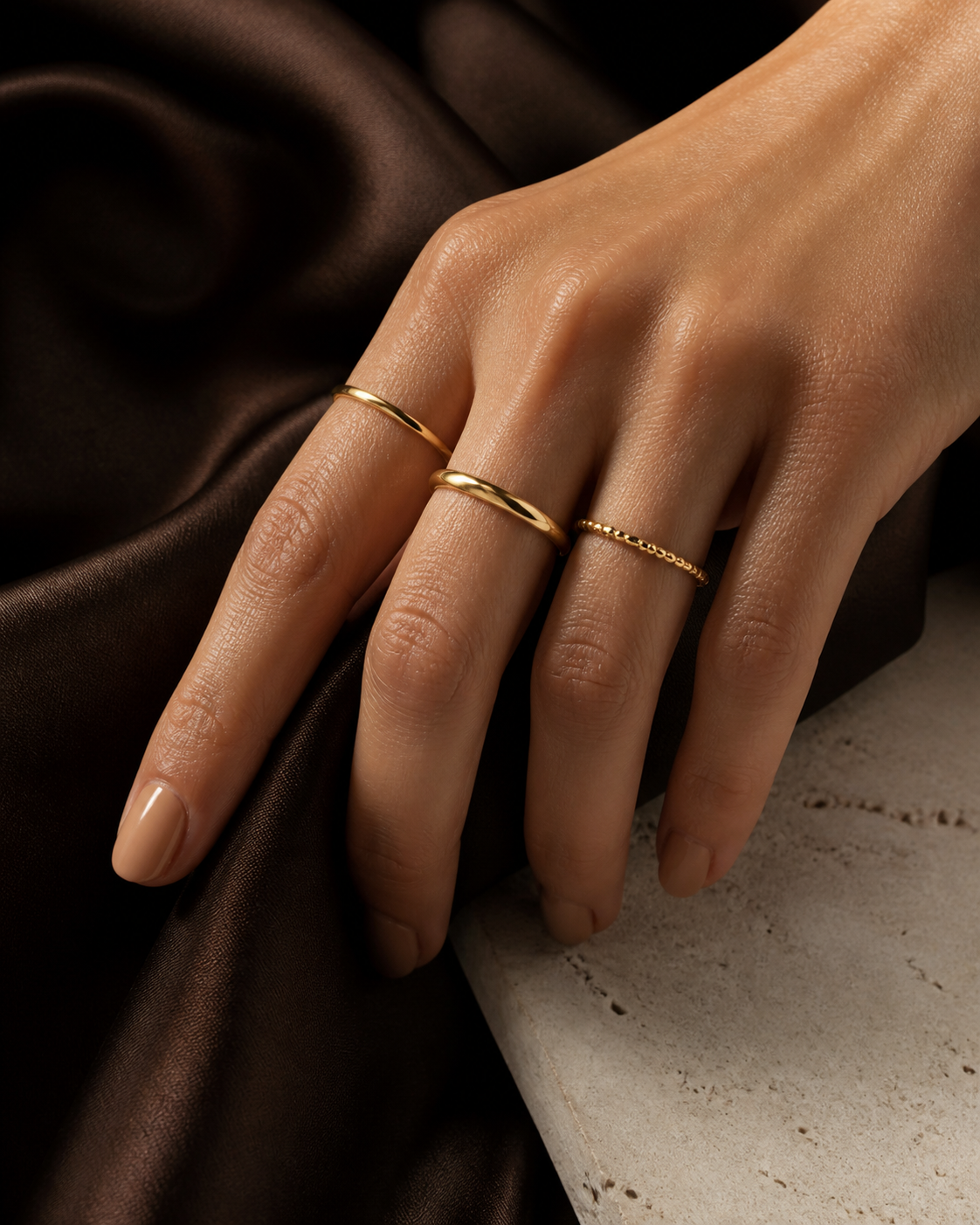 Woman wearing a refined stack of gold Zyvora rings on espresso silk