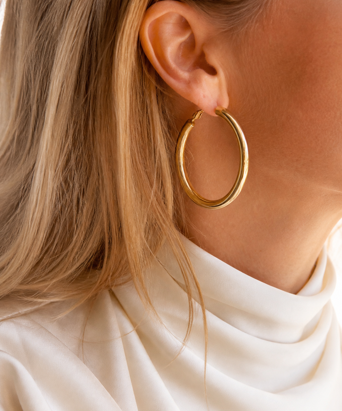Model wearing Evara Statement Hoops in gold [finish:gold]