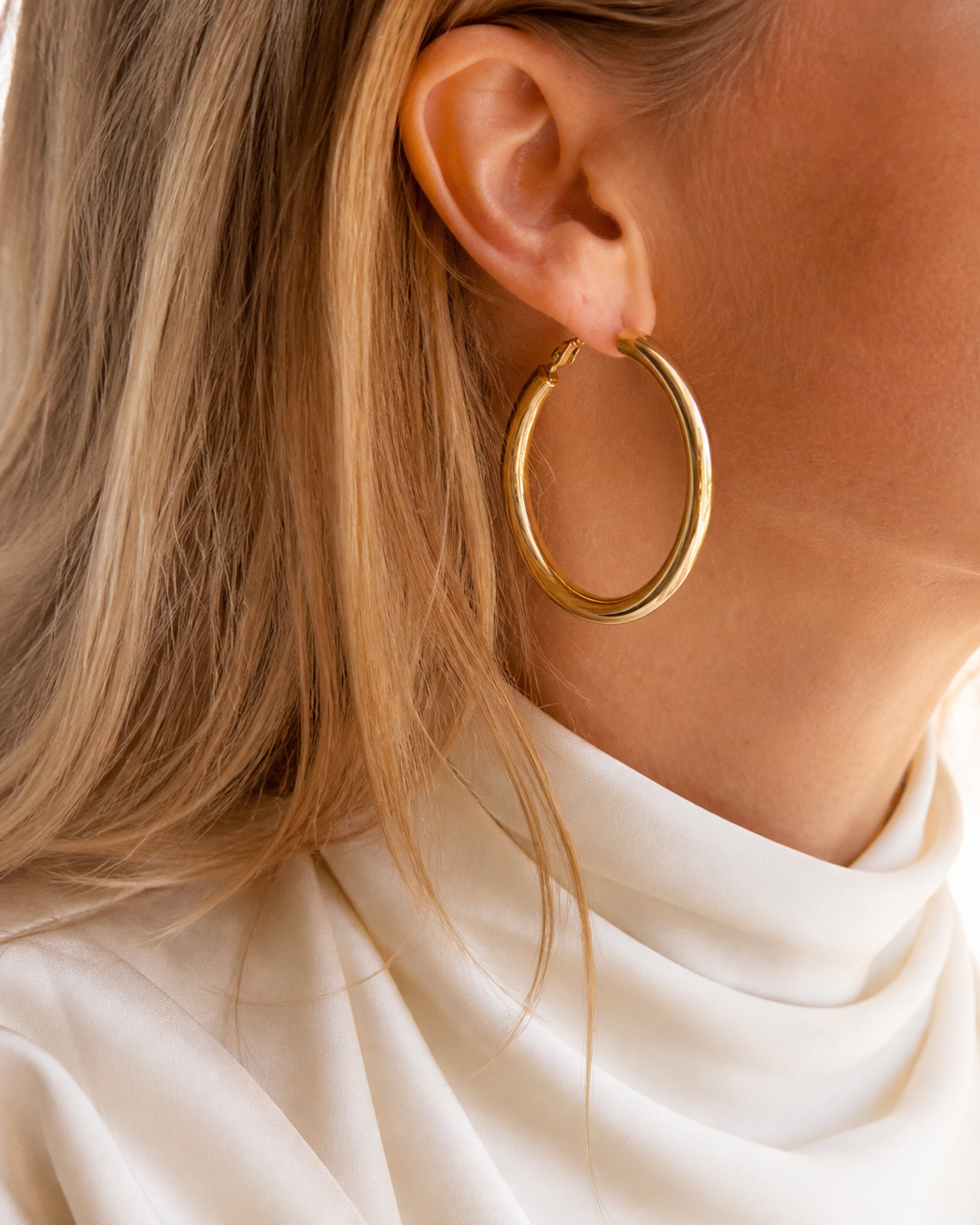 Model wearing Evara Statement Hoops in gold [finish:gold]