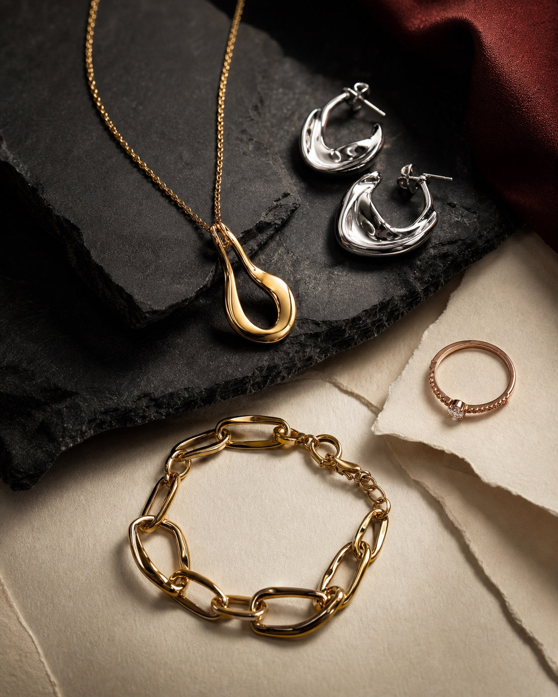 Gold, silver, and rose-gold tone jewelry arranged on stone and paper