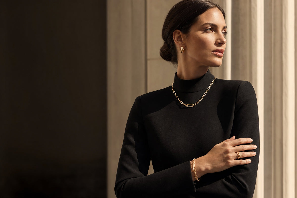 Model wearing gold-tone Zyvora jewelry in a black tailored look